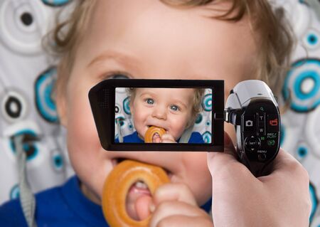 pretty baby boy laughing portrait with bread ring recording at camcorderの写真素材