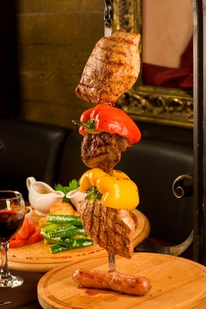 Big tasty roasted meat cuts at skewer on a decorated tableの写真素材