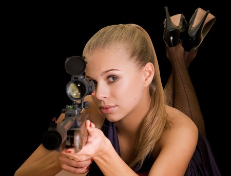 Beauty blond girl with a gun on a black backgroundの写真素材