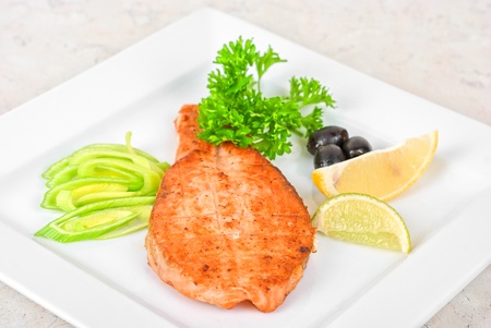 Grilled salmon steak with greens,onion, lemon, lime and oliveの写真素材