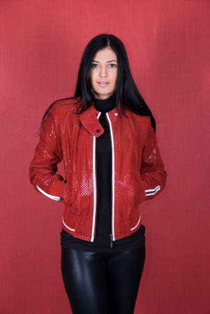 beautiful woman in a red jacket on a red backgroundの写真素材