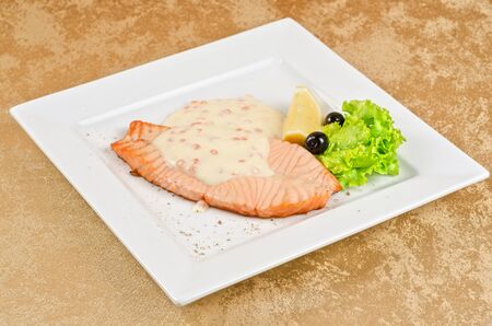 Grilled salmon steak with greens, lemon, sauce and pepper chileの写真素材