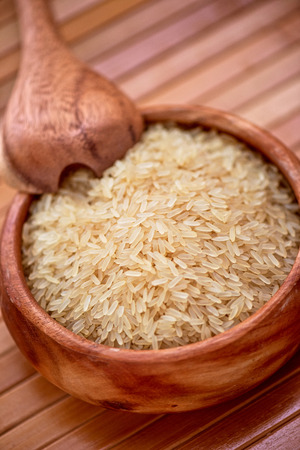 golden rice on wooden plate on wooden backgroundの写真素材