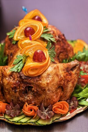 Whole roasted chicken with vegetables and fruits on wooden tableの写真素材