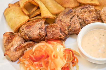 Grilled pork, baked potatoes and vegetable saladの写真素材