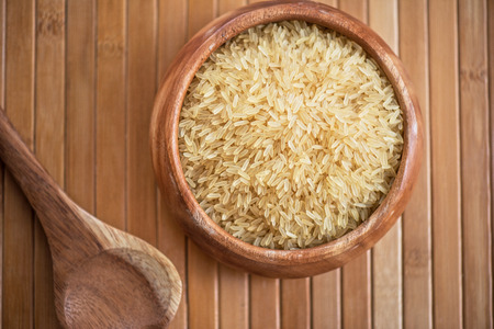 golden rice on wooden plate on wooden backgroundの写真素材