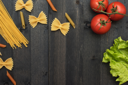 food background on rustic wood with pasta and tomatoesの写真素材
