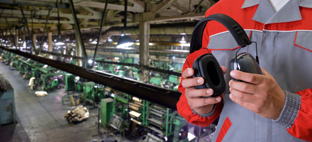 Worker with protective headphone at man hands at industrial factoryの写真素材