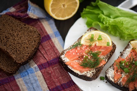 Homemade sandwich with salmon and rye bread , butter lemon, and lettuce for breakfastの写真素材