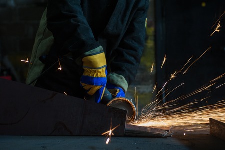 worker welding metal with sparks at factory