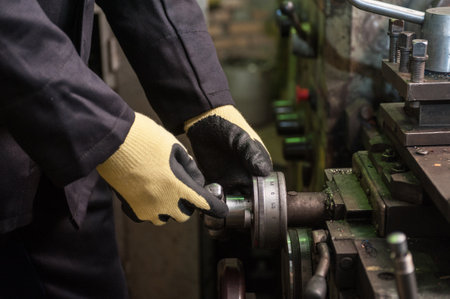 worker in protective gloves in factory using machineの写真素材