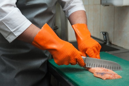 Chef cutting salmon fish on fillet with knifeの写真素材