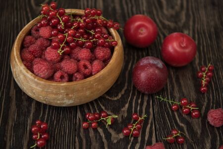 Fresh berries raspberry and red currant in bowl on wooden table
