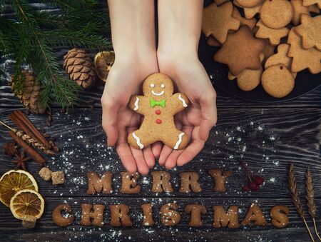 Woman hands keep gingerbreads for new years and christmas on wooden background with space for design