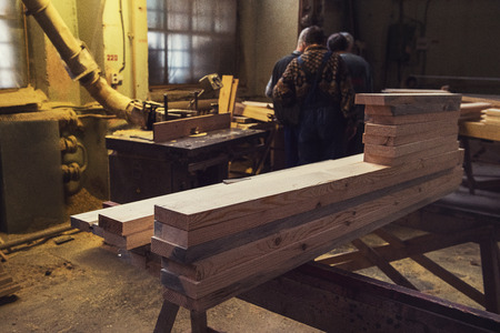 Stack of wooden blanks at the sawmill. Workers on background.