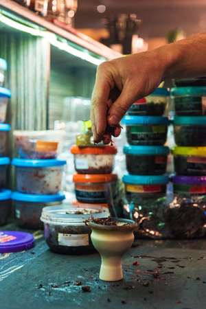 Shisha hookah preparing by barman. Bartender lays tobacco for smoking in hookahの写真素材