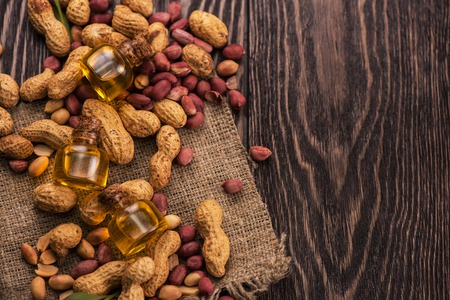 Natural peanuts with oil in a glass jar on the wooden backgroundの写真素材