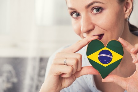 Young woman with gingerbread heart cookies with flag of Brazilの写真素材