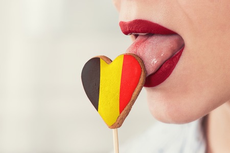 Closeup photo of the woman lips and cookie hearts with flag of Belgiumの写真素材