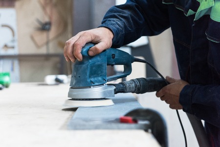 Furniture production or craft concept: worker polishing the stone surface of furniture part with polish machineの写真素材