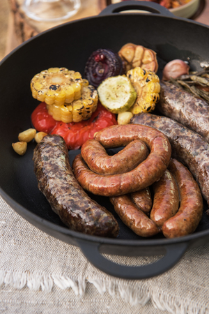 Grilled different meat sausages with vegetables and spicesの写真素材