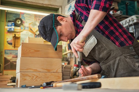Carpenter working with a chisel and hammer in a wooden workshop. Profession, carpentry and manual...