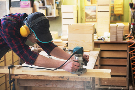 Worker grinds the wood box of angular grinding machine. Profession, carpentry and woodwork concept.の写真素材