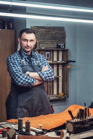 Man working with leather textile r at a workshop. Male portrait. Concept of handmade craft...