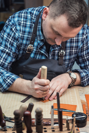 Man working with leather textile at a workshop. Craftman cutting leather. Concept of handmade craft...
