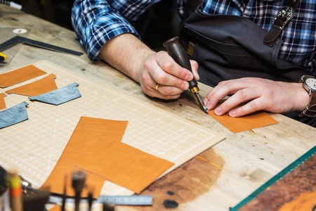 Man working with leather textile at a workshop. Concept of handmade craft production of leather...