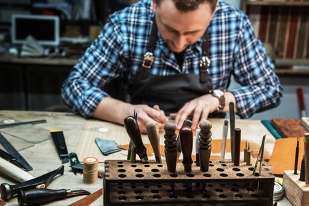 Man working with leather textile at a workshop. Concept of handmade craft production of leather...