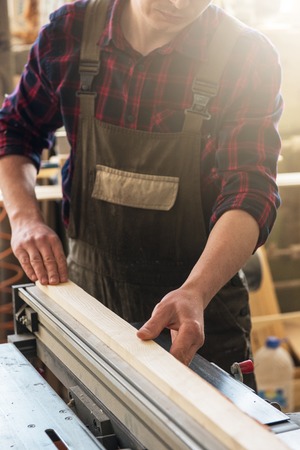 The worker makes measurements of a wooden board with corner ruler. Profession, carpentry and woodwork concept.の写真素材