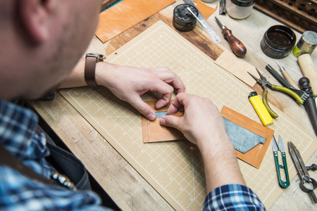 Man making leather wallet at a workshop. Concept of handmade craft production of leather goods.の写真素材