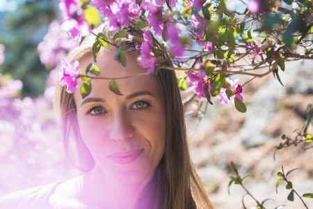 Portrait of young beauty woman in purple rhododendron flowers.