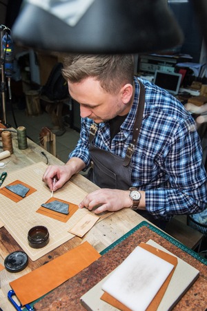 Man working with leather textile at a workshop. Male portrait.