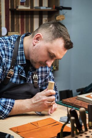 Man working with leather textile at a workshop. Craftman cutting leather. Concept of handmade craft...