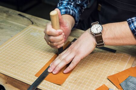 Man working with leather textile at a workshop. Craftman cutting leather. Concept of handmade craft...