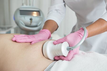 Closeup photo of fat man with big belly having cavitation procedure removing cellulite on abdomen in...
