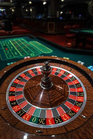 Casino, gambling and entertainment concept - roulette table and stack of poker chips