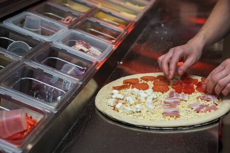 Closeup hand of chef baker making pizza at kitchen of pizzeria