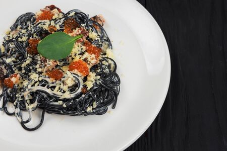 Black pasta with cuttlefish ink, parmesan cheese basil and red caviar. The concept of Italian cuisine.の写真素材