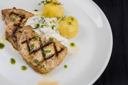 Grilled pork meat with sauce and potato on white plateの写真素材