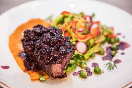 Roasted beef with berries sauce garnished with vegetablesの写真素材
