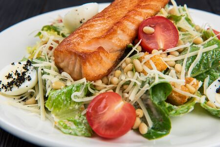 Grilled salmon caesar salad with croutons, parmesan, pine nut and quail eggの写真素材