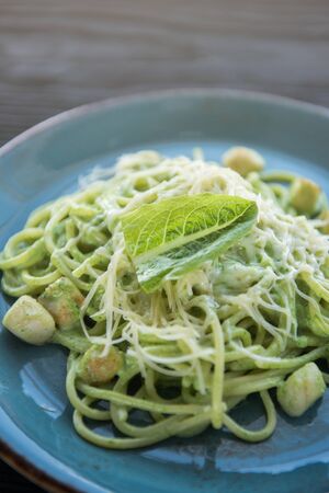 Green Pasta with scallop and sauce on blue plateの写真素材
