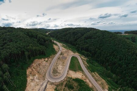 Aerial top vew of winding road in the mountains, drone shot. Altai Krai, Western Siberia, Russia....
