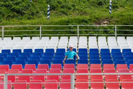 Lonely boy on the empty stadium outdoor. Empty tribune due to pandemic Covid-19. Concept of pandemic life , empty stadiums, distance from viewers, safety.の写真素材