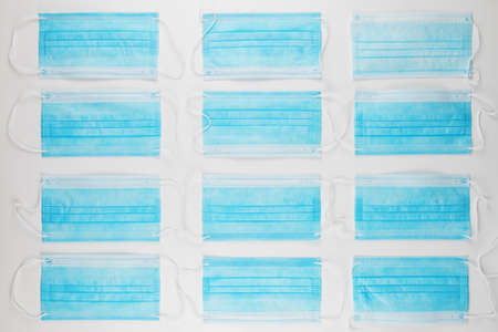 Medical masks on the white background for protection from coronavirus. Epidemic and healthcare concept, pattern, flat lay.の写真素材
