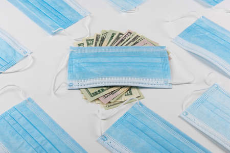 Sell - buy medical face mask concept. Protective face masks and nany US dollars banknotesの写真素材