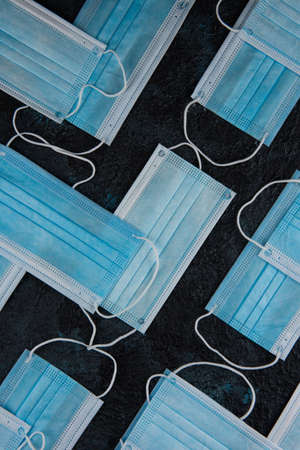 Medical masks on the dark colored background for protection from coronavirus. Epidemic and healthcare concept, pattern, flat lay.の写真素材